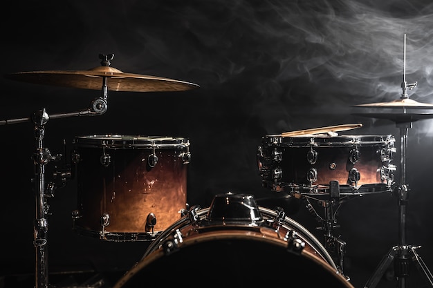Drum kit su uno sfondo scuro con illuminazione scenica, copia spazio.