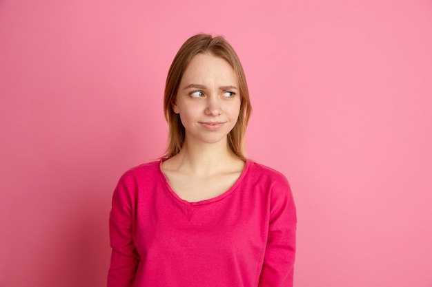 Dubbio, incertezza. Ritratto della giovane donna caucasica in studio rosa