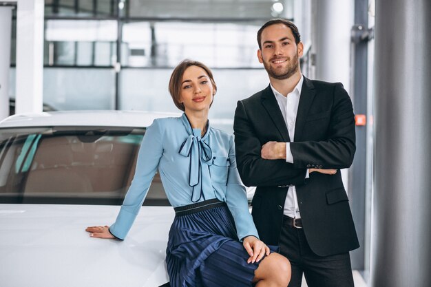 Due addetti alle vendite femminili e maschii ad una sala d&#39;esposizione dell&#39;automobile