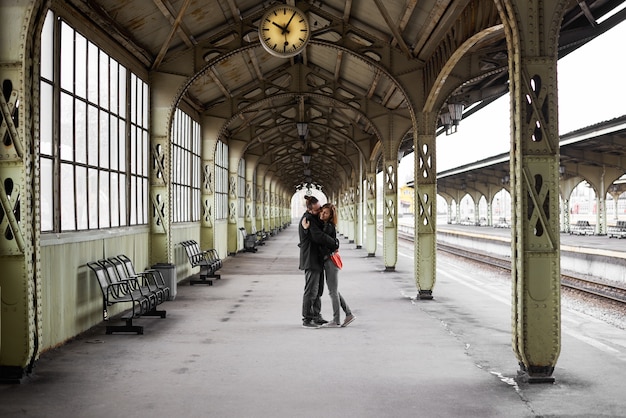 Due amanti si abbracciano e si baciano sulla stazione ferroviaria