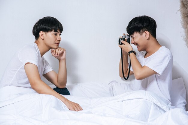 Due amati giovani uomini si sono seduti sul letto e hanno scattato foto con la telecamera.