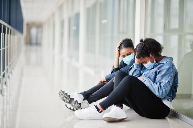 Due amiche africane in giacca di jeans che indossano maschere protettive Concetto di virus salute medica