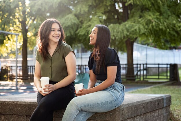 Due amiche che bevono una tazza di caffè insieme al parco