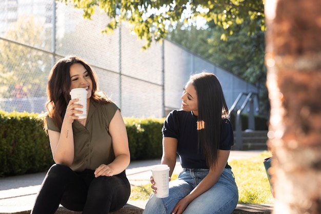 Due amiche che bevono una tazza di caffè insieme al parco