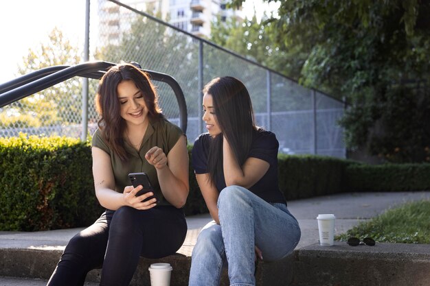 Due amiche che usano lo smartphone nel parco