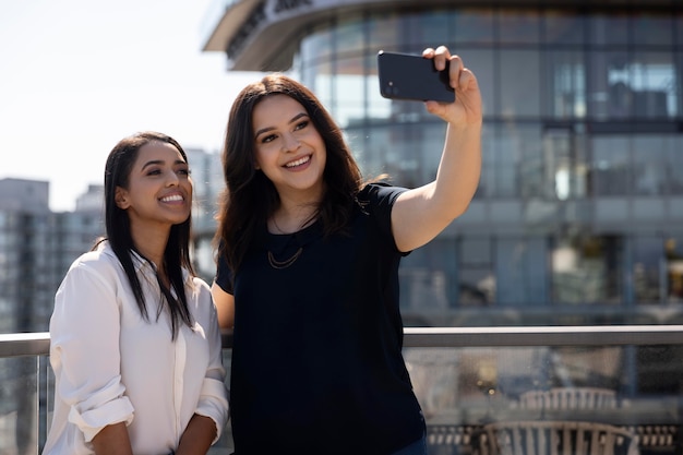 Due amiche su una terrazza sul tetto si fanno un selfie