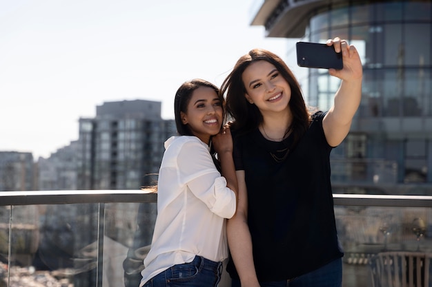 Due amiche su una terrazza sul tetto si fanno un selfie