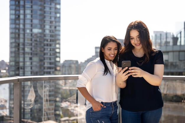 Due amiche su una terrazza sul tetto usando lo smartphone