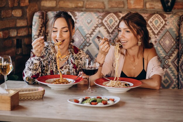 Due amici di ragazze che mangiano pasta in un ristorante italiano