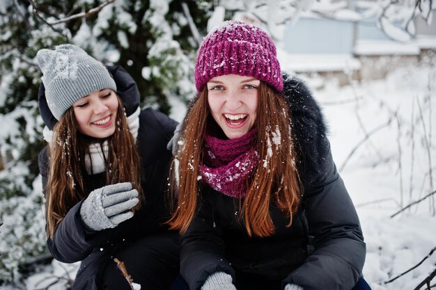 Due amici di ragazze divertenti che si divertono in una giornata nevosa invernale vicino ad alberi innevati