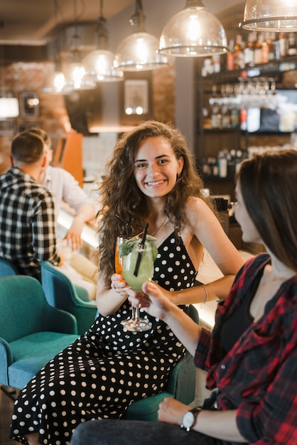 Due amici femminili che godono del cocktail nel pub