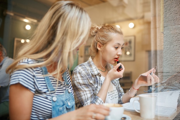 Due amici femminili che si siedono all'interno del caffè e che hanno caffè