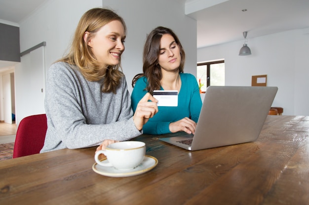 Due amici femminili felici che per mezzo del computer portatile