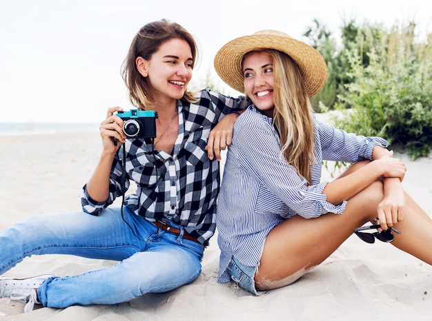 Due amici femminili felici divertendosi sulla spiaggia