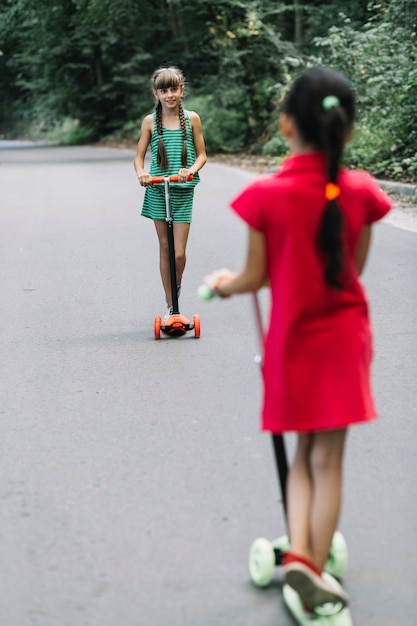 Due amici femminili in piedi sul motorino a guardare l&#39;altro