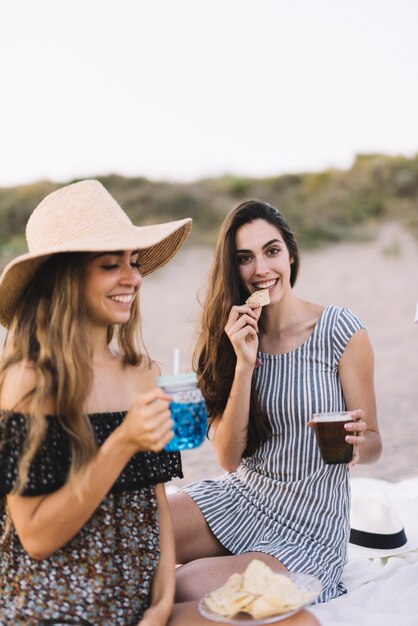 Due amici femminili seduti sulla spiaggia sorridente