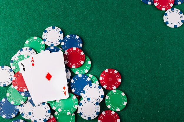 Due assi giocando a carte e fiches sul tavolo da poker verde