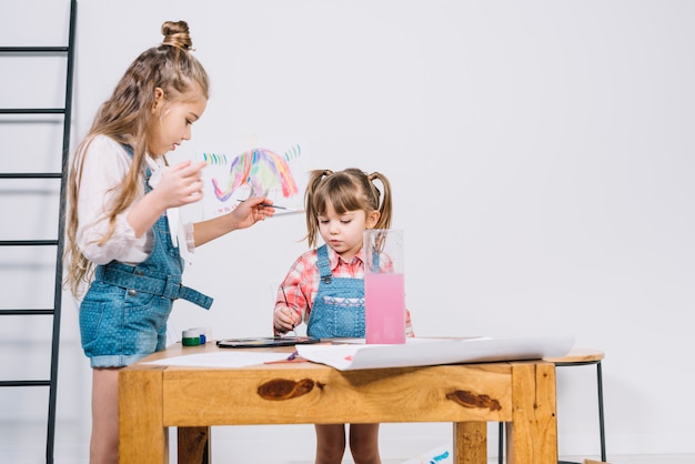 Due bambine che dipingono con aquarelle su carta