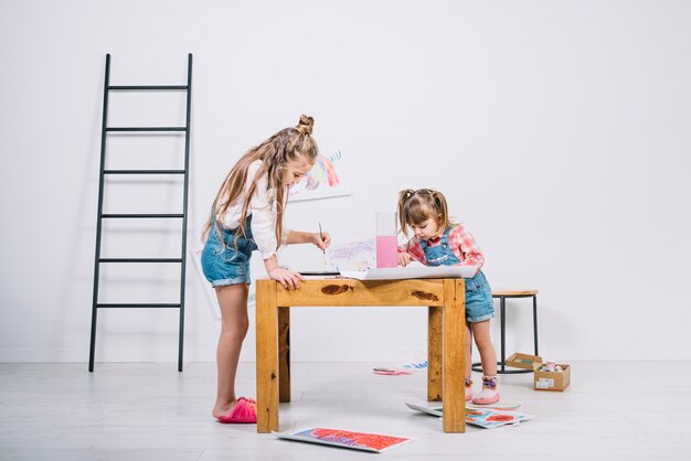 Due bambine che dipingono con l&#39;aquarelle al tavolo