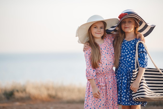 due bambine in vestito e cappello all'aperto