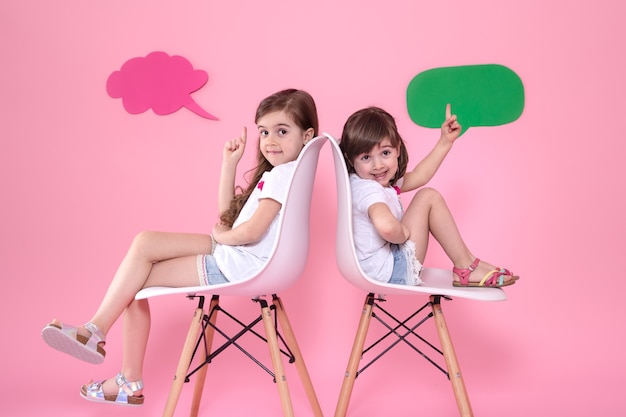 Due bambine sulla parete colorata con icone di discorso