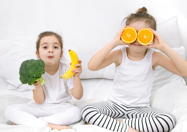 Due bambini carini felici giocano con frutta e verdura sulla luce.