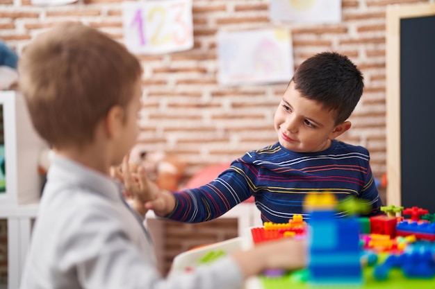 Due bambini che giocano con i blocchi di costruzione seduti sul tavolo all'asilo