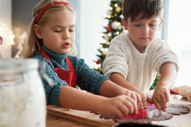 Due bambini che tagliano i biscotti del pan di zenzero