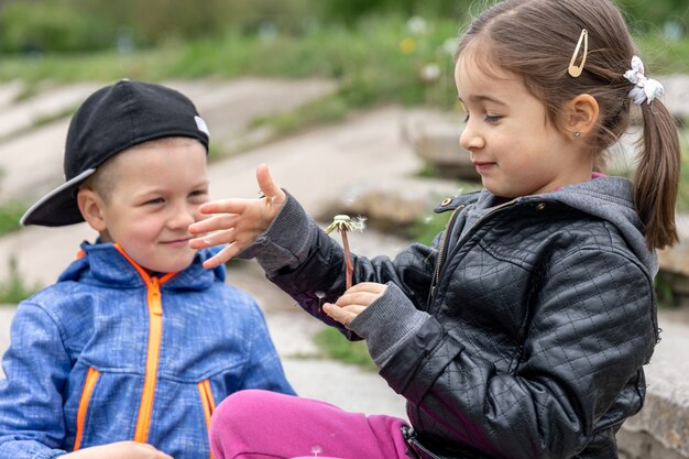 Due bambini piccoli stanno giocando con i denti di leone durante una passeggiata