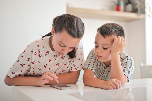 Due bambini usano uno smartphone in cucina