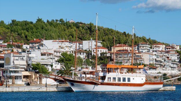 Due barche a vela ormeggiate vicino a un molo a Neos Marmaras, edifici situati su una collina con vegetazione multipla, Grecia