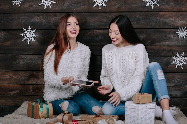 Due belle donne sedute per terra con una tavoletta, tra i regali di Natale