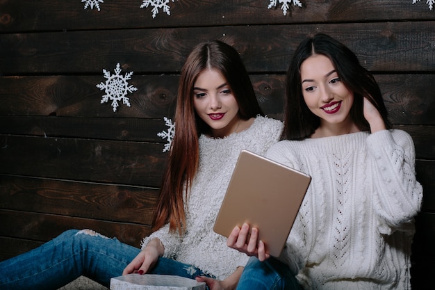 Due belle donne sedute sul pavimento con un tablet