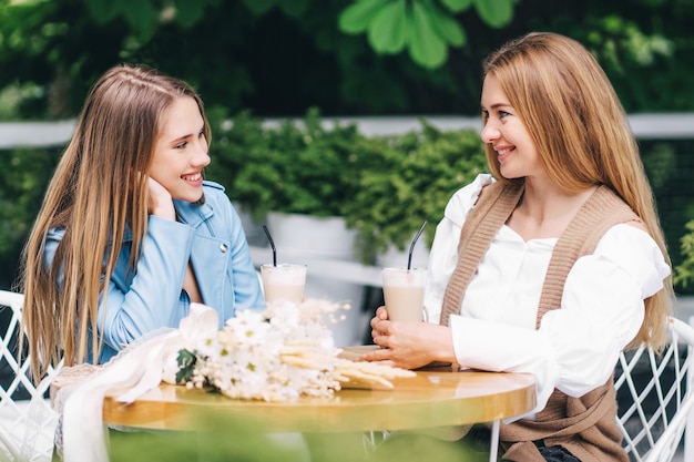 Due belle donne sono sedute a un tavolo in una caffetteria e comunicano emotivamente