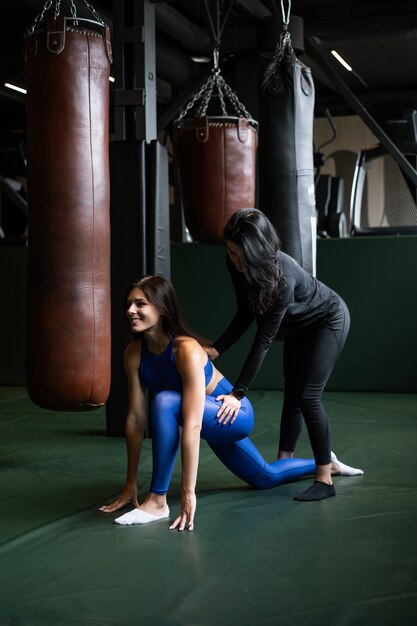 Due belle ragazze che fanno forma fisica in una palestra. Allungando i muscoli della schiena e delle gambe.