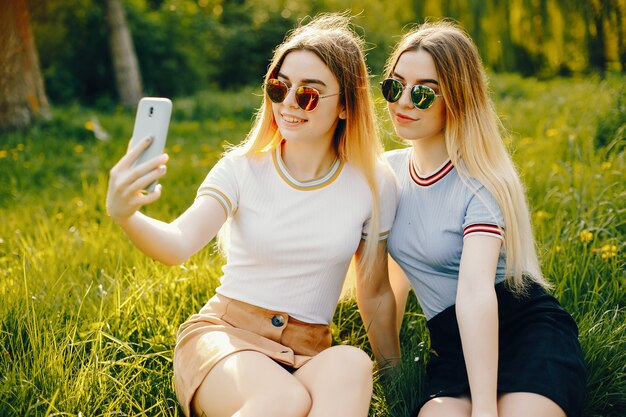 due belle ragazze giovani e belle con i capelli biondi lucenti e una gonna e sitiing con il telefono