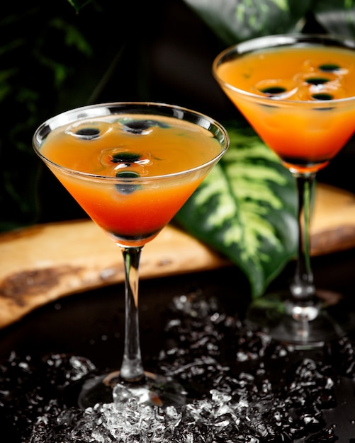Due bicchieri di agrumi cocktail in bicchieri martini guarniti con cubetti di ghiaccio d'oliva