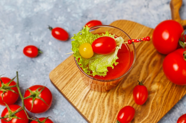 Due bicchieri di succo di pomodoro fresco e pomodori sulla superficie di cemento grigio