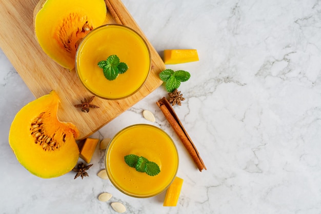 due bicchieri di succo di zucca posto sul pavimento di marmo bianco