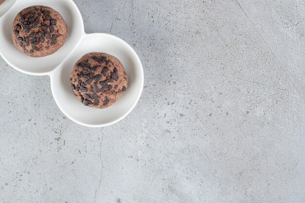 Due biscotti con gocce di cioccolato su un piatto su una superficie di marmo