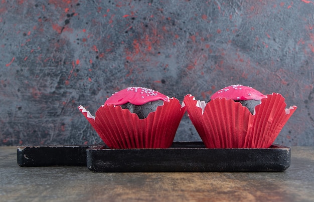 Due ciambelle dolci al cioccolato con glassa rosa e spruzza