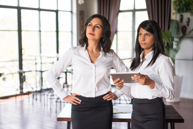 Due colleghe femminili seri che utilizzano il pc della compressa nel ristorante.