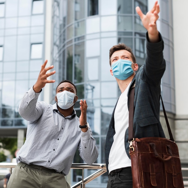 Due colleghi all'aperto durante la pandemia che indossano maschere mediche