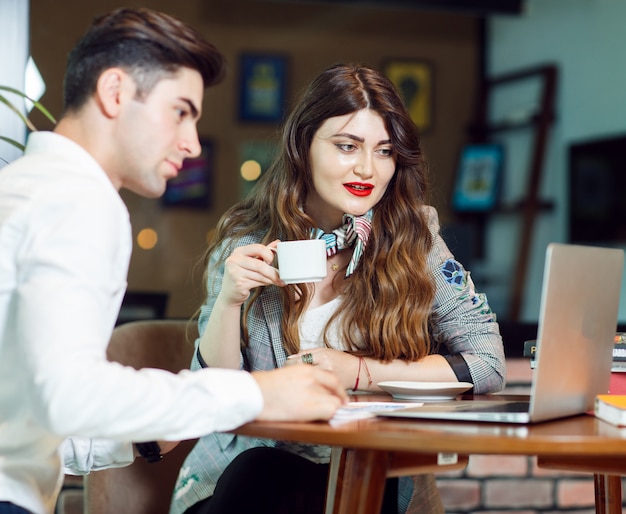 Due colleghi che hanno coffea e controllano un progetto nella zona di seduta di un ufficio.