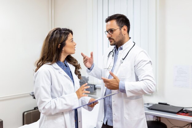 Due colleghi medici in camice bianco che tengono appunti Sono così riusciti a sorridere e lavorare in squadra insieme