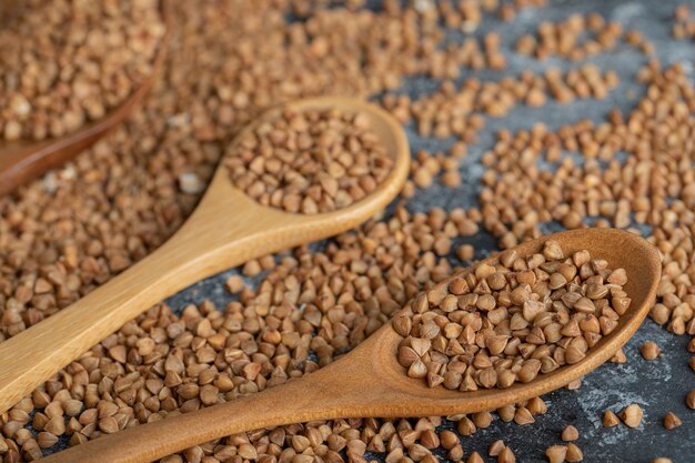 Due cucchiai di legno pieni di grano saraceno crudo