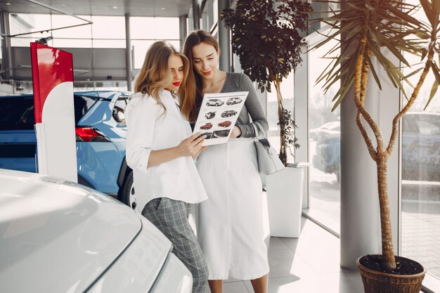 Due donne alla moda in un salone di auto