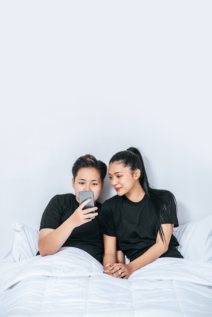Due donne amorevoli che dormono e giocano con gli smartphone.