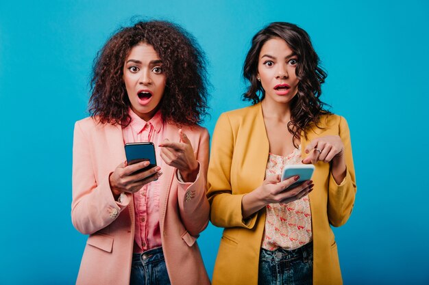 Due donne castane che tengono smartphone