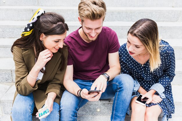 Due donne che guardano lo schermo del telefono cellulare dell&#39;uomo